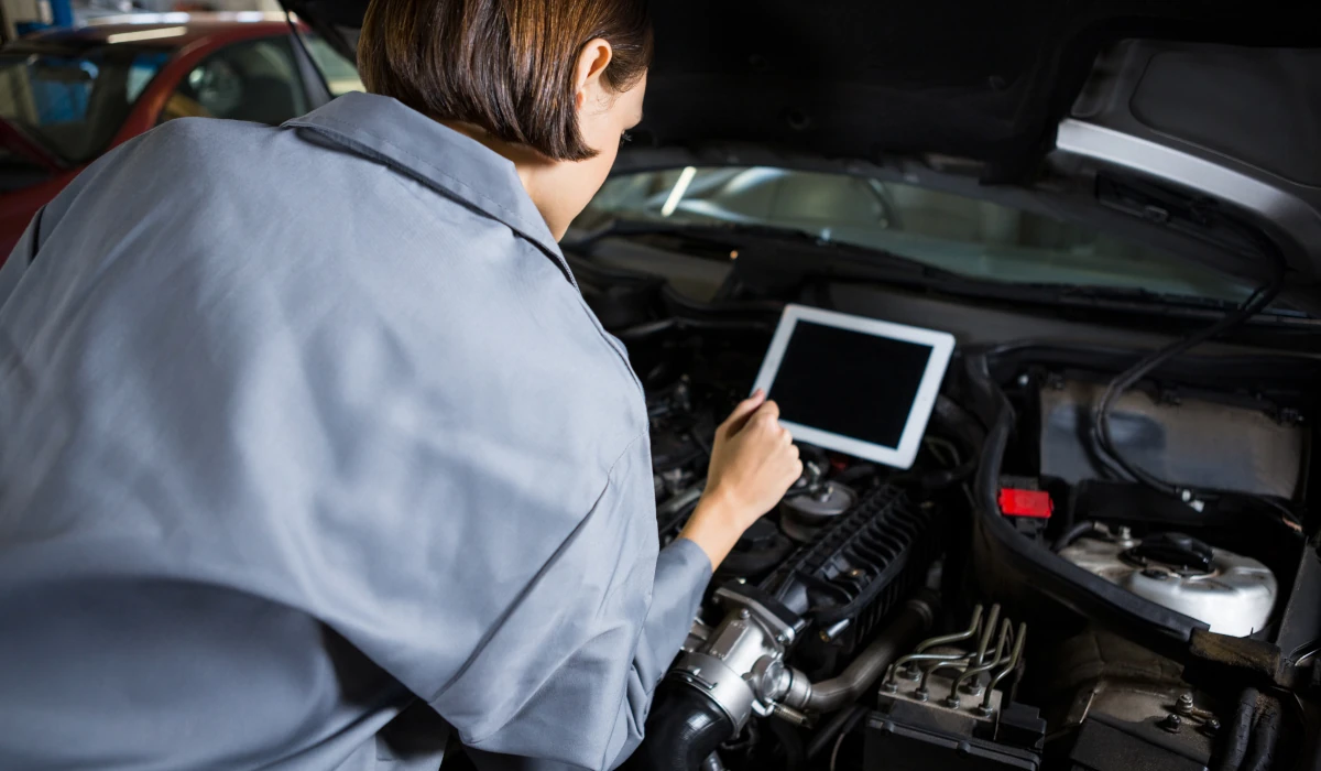 Foto de uma mulher mecânica utilizando um scanner em um automóvel