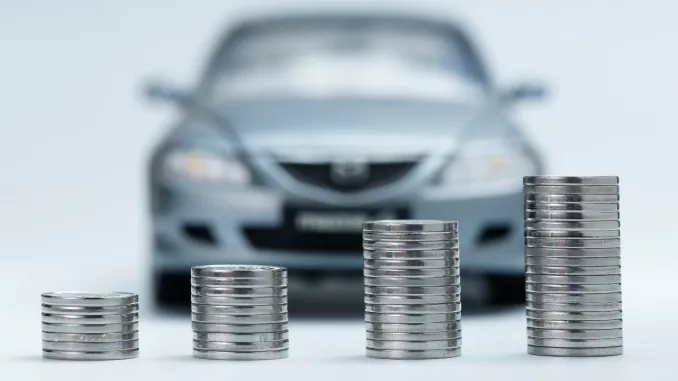 Imagem de moedas com um carro atrás em referência a Gastos com o automóvel é a segunda maior despesa familiar